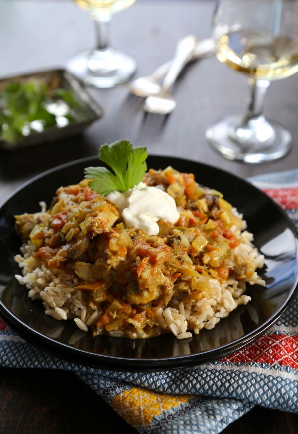 Black plate with rice and Jamaican crab stew, garnished with sour cream and cilantro.