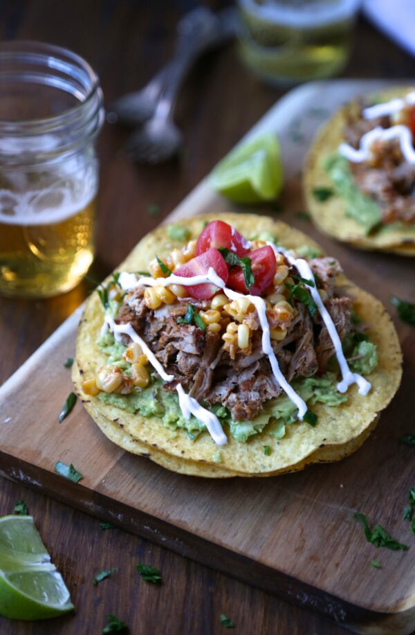 Tostadas topped with avocado, ribs, corn, tomatoes and crema. 