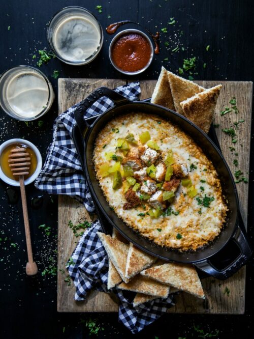 hot chicken dip with honey toasts on a table