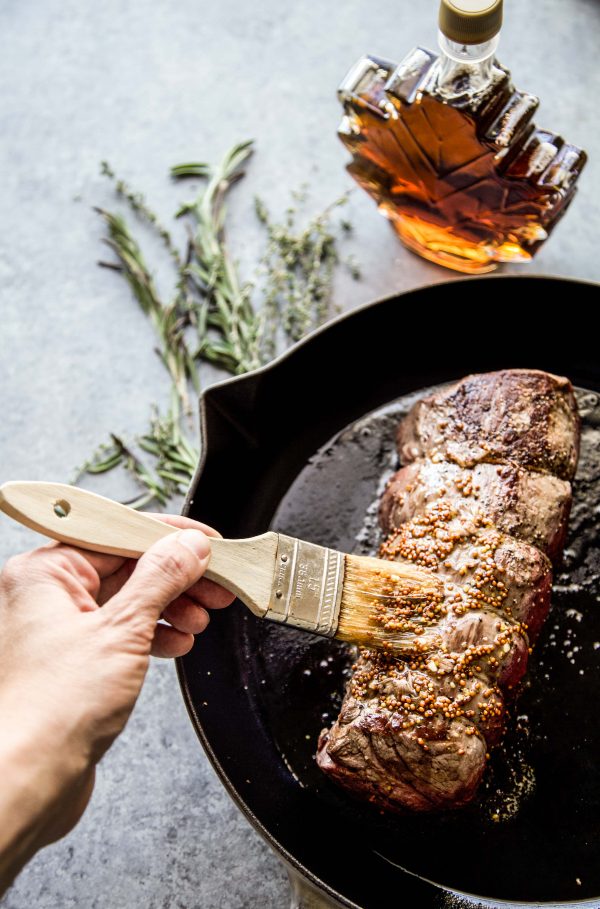 maple mustard glaze being brushed onto beef tenderloin