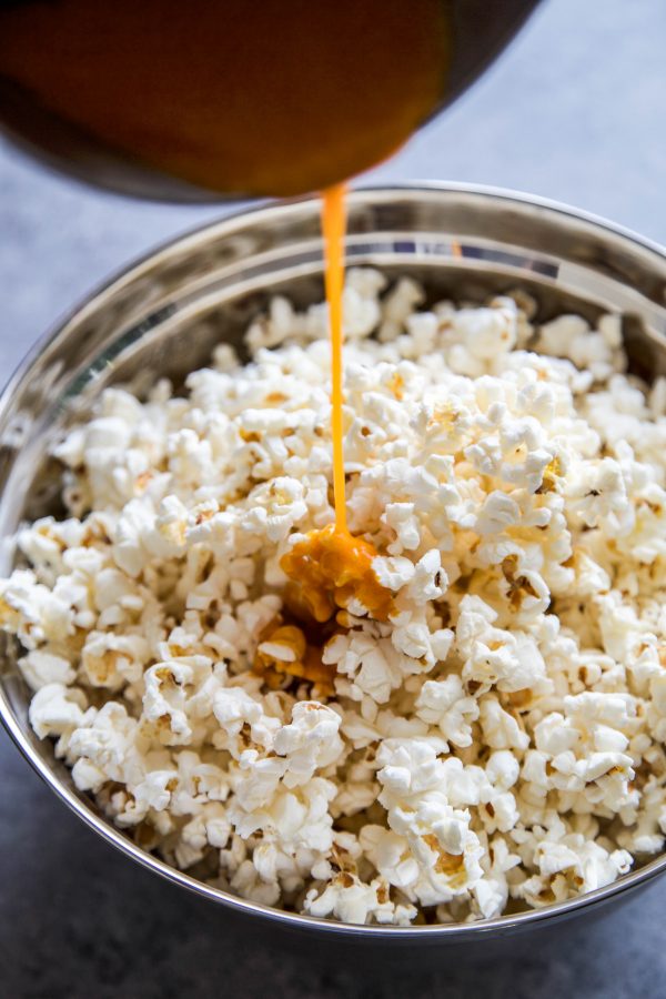 buffalo wing sauce being poured onto popped popcorn