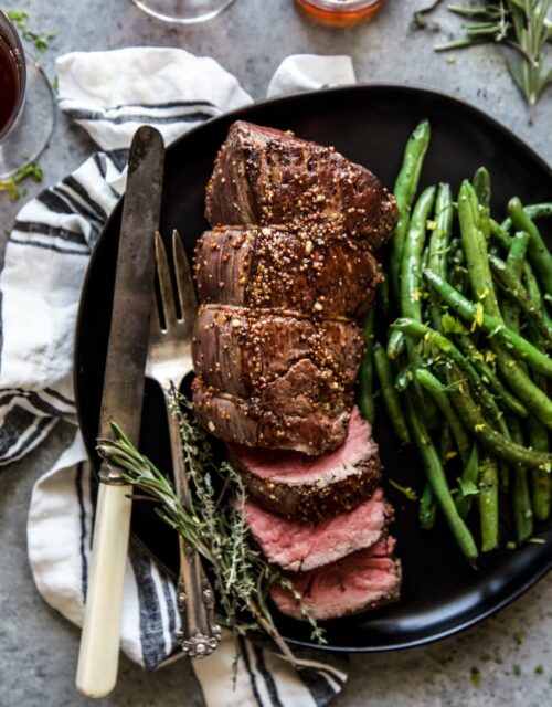 roasted beef tenderloin on a plate with green beans