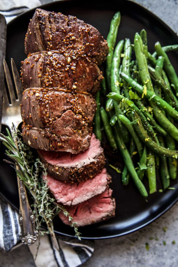 roasted beef tenderloin on a plate with green beans