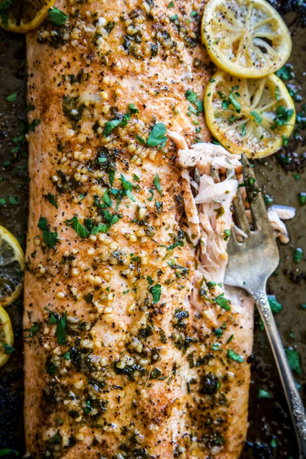 Baked cajun salmon on a sheet pan with a fork digging into the flaky fish.