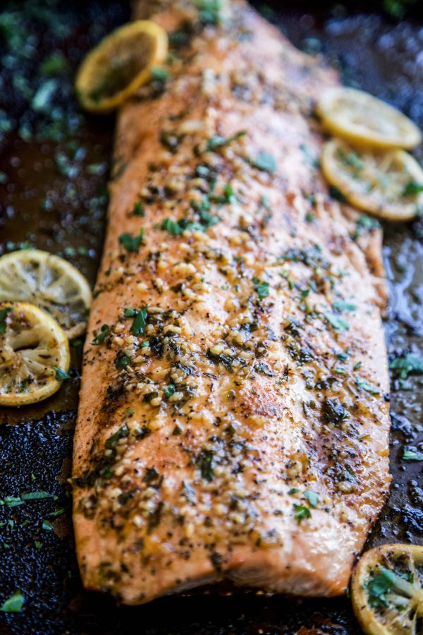 Baked salmon on a sheet pan, covered with spices and sliced lemon.