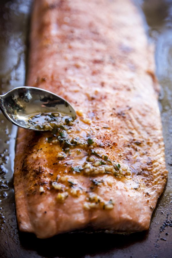 Garlic and butter sauce being put on salmon with a spoon.