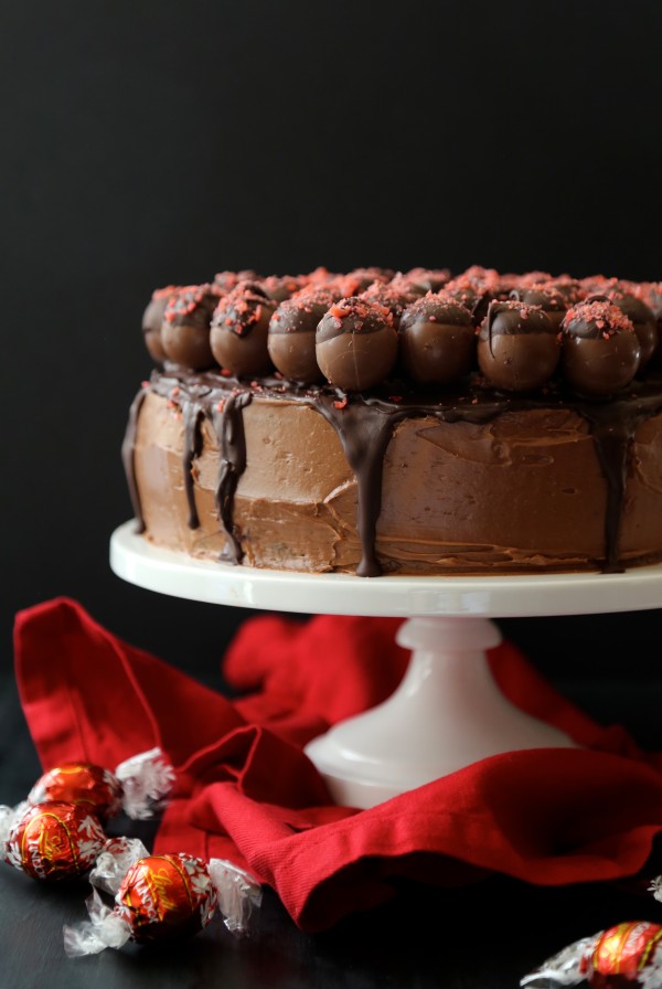 dark chocolate cake with cherry pop rocks covered truffles on a pedestal 