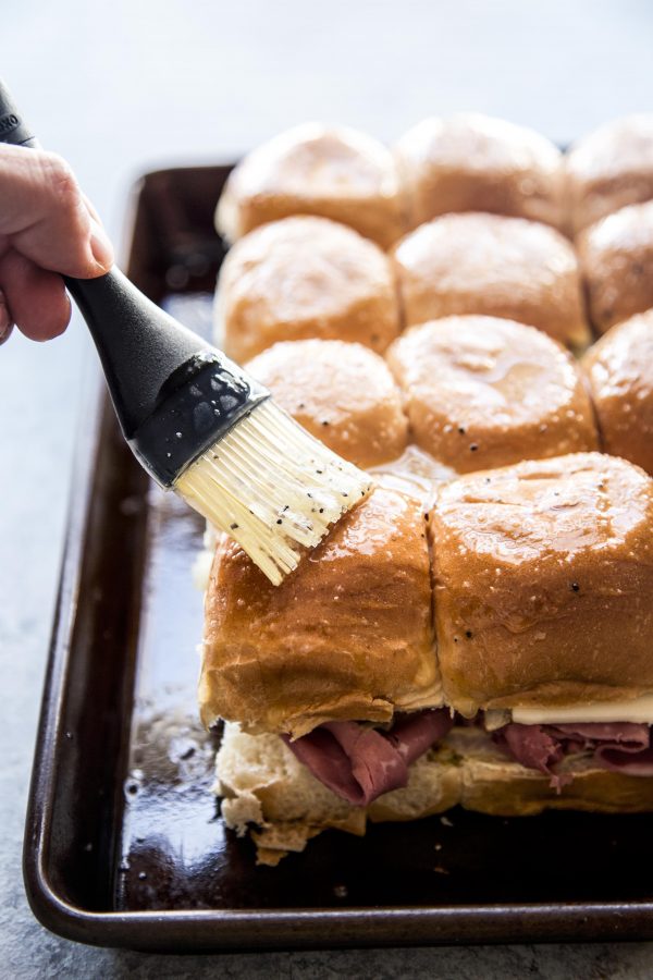 melted butter being brushed onto corned beef sliders
