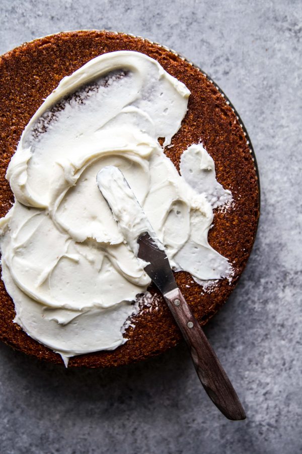 honey cake being frosted with citrus vanilla frosting