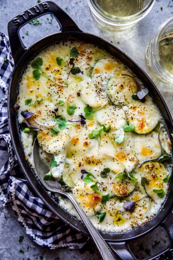Baked Cheesy Scalloped Zucchini in a casserole dish with a spoon in it. 
