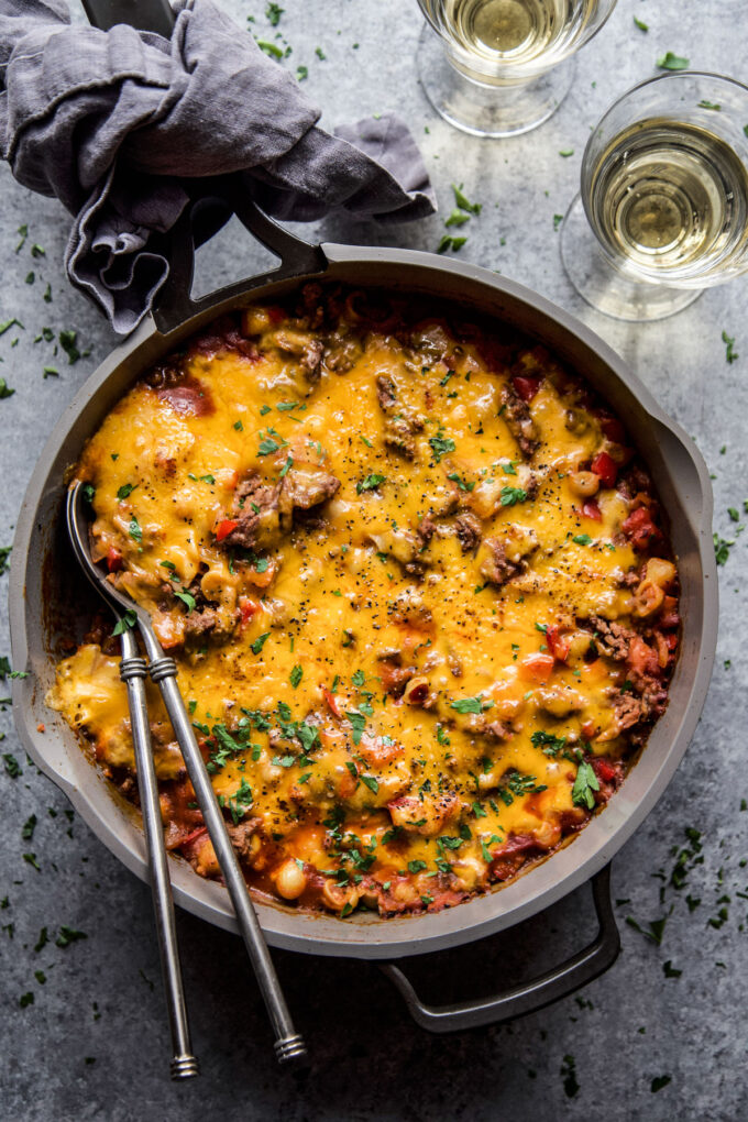 Turkey Sloppy Joe Casserole in a skillet with melted cheese on top and two spoons in the pan.