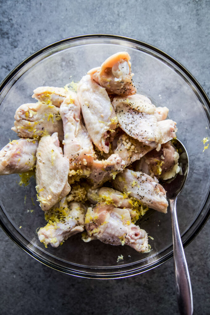 chicken wings marinating in a bowl with lemon garlic marinade
