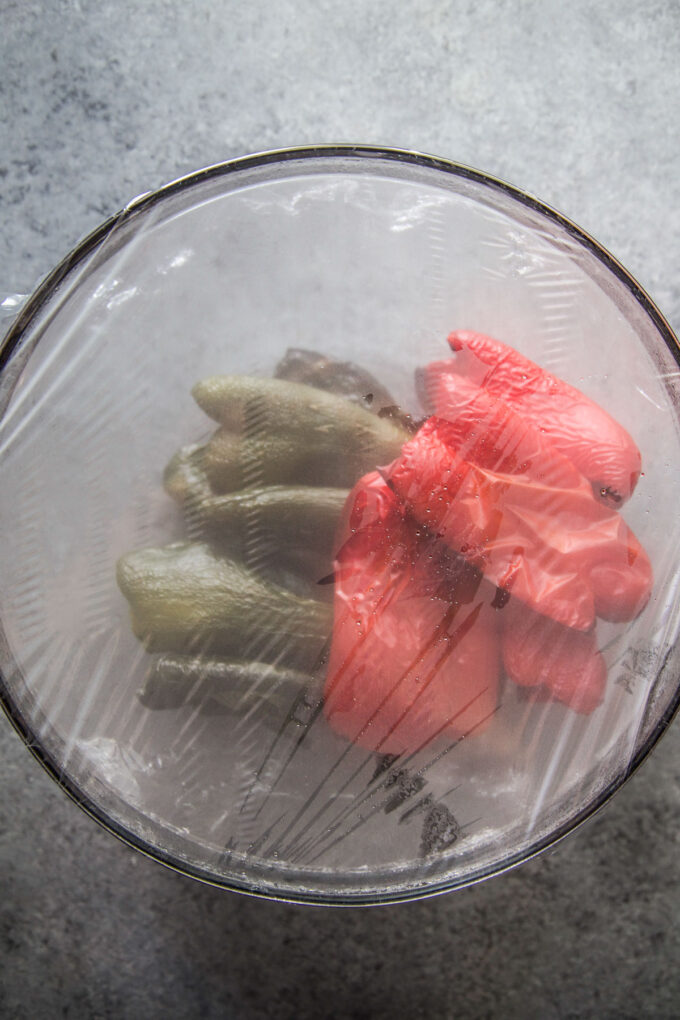 peppers and poblanos covered in a bowl with plastic wrap