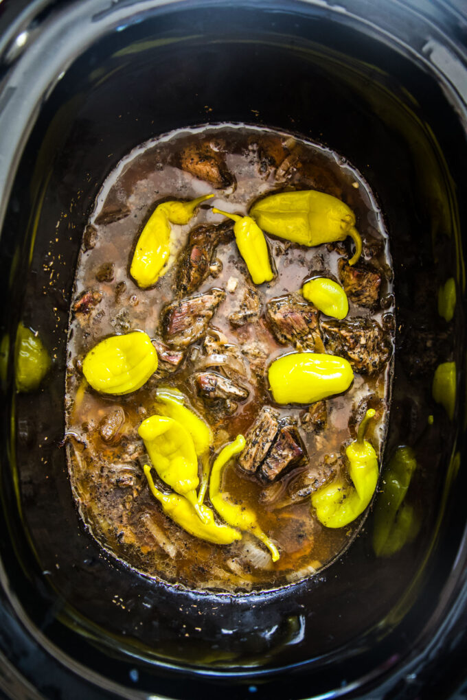 slow cooker shredded pot roast before cooked after 8 hours with peppers